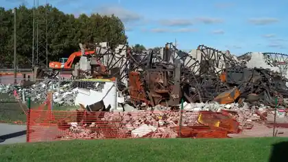 Burnt steel and debris with an excavator on a commercial demolition site