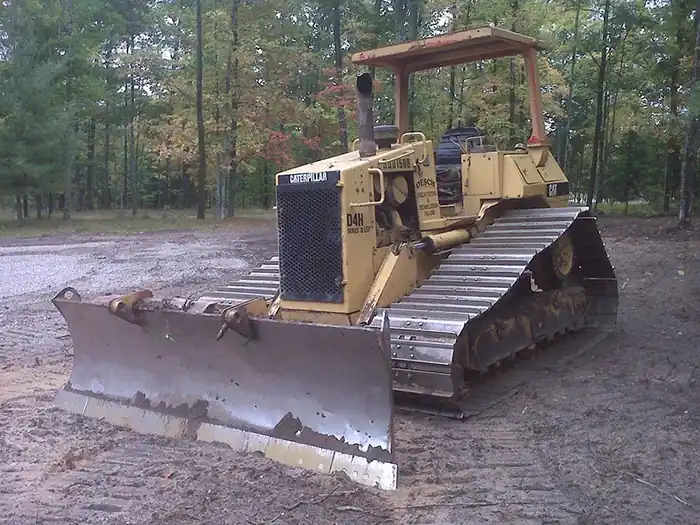 Yellow CAT bulldozer with its blade raised on cleared ground