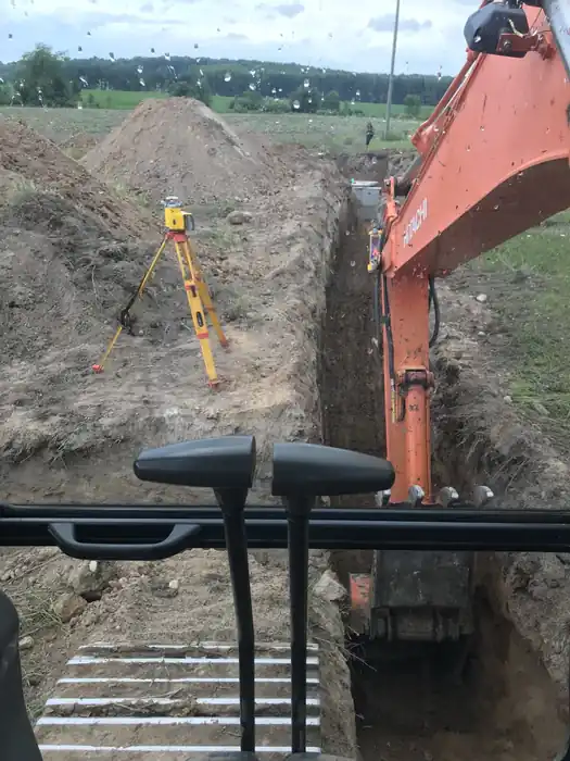 Laser grade rod standing in a fresh trench, seen from inside the excavator cab