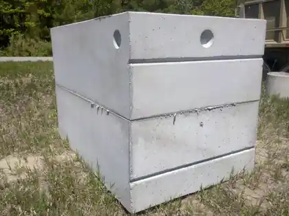 Precast concrete septic tank with two round inlet and outlet openings on a grass lot