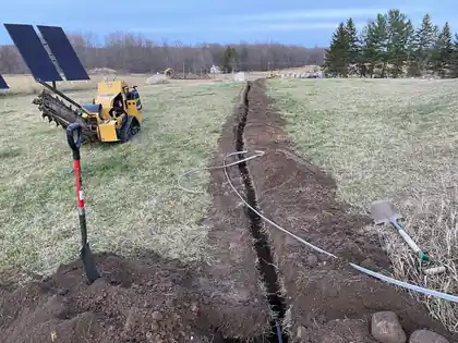Open trench cut across a field for a ground-mount solar array feed line