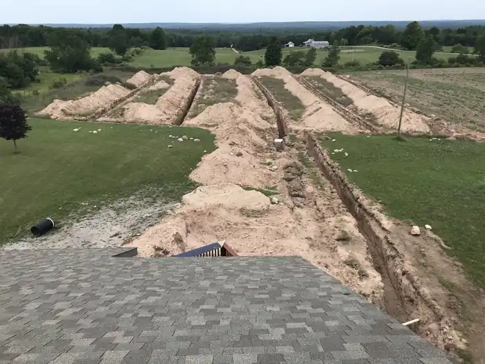 Trench cut across an open field by an Oesch excavator